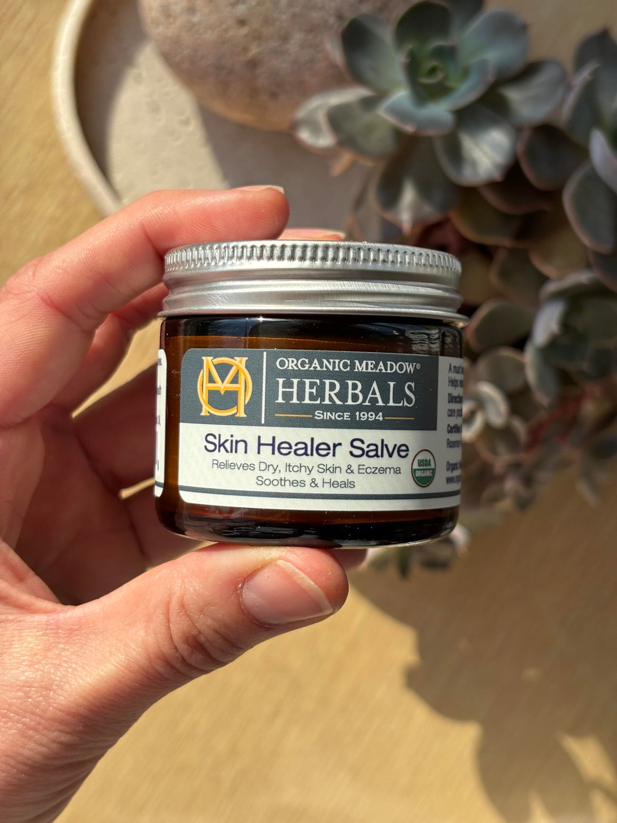 Organic Meadow Herbals salve being applied to a hand to relieve dryness