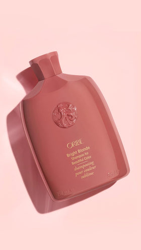 Oribe Bright Blonde 8.5 oz bottle next to a hand for size and scale reference