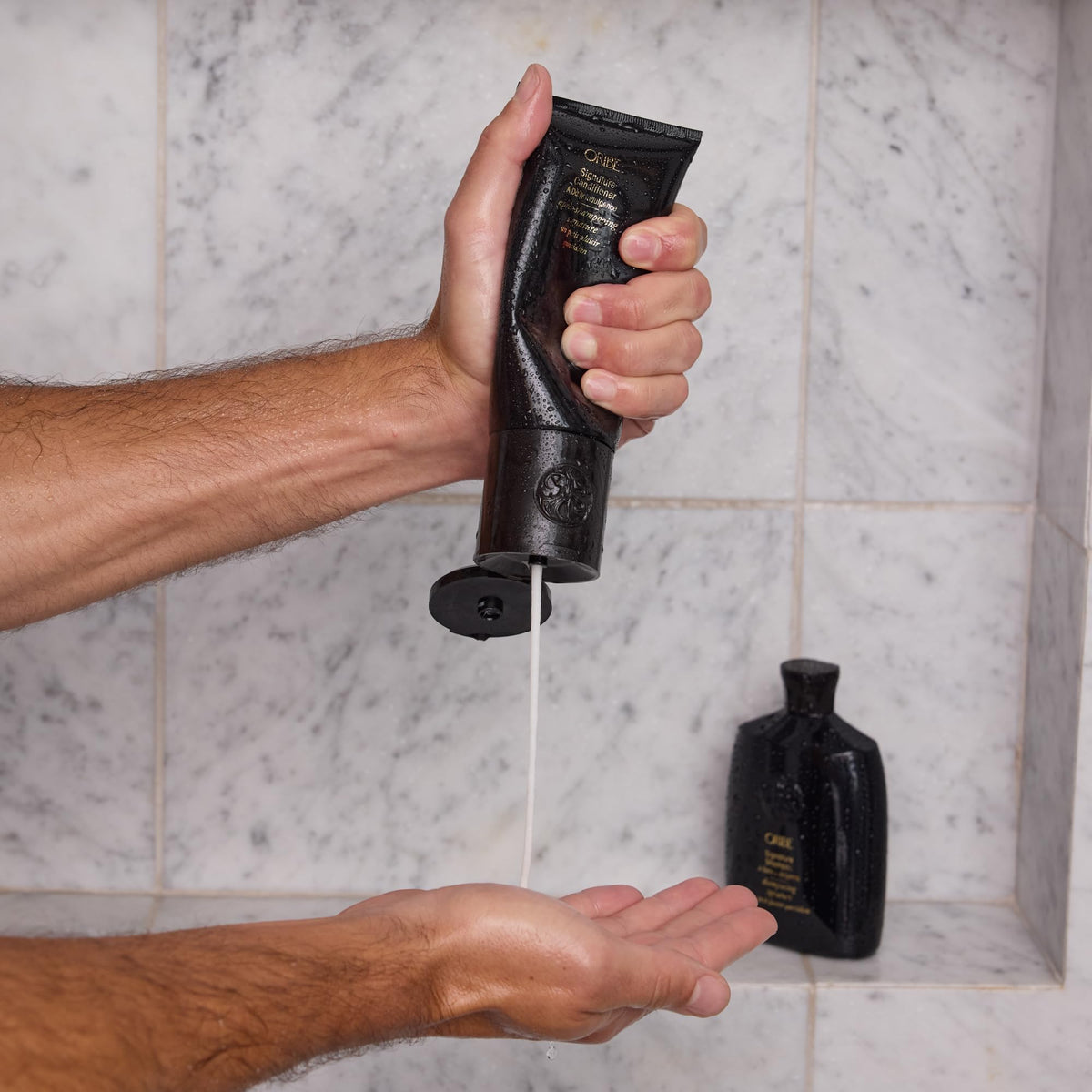 Oribe conditioner dab on palm demonstrating lightweight, hydrating cream