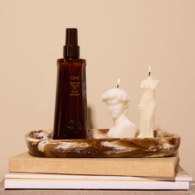 Oribe Maximista on bathroom vanity beside brush highlighting salon-quality routine benefit