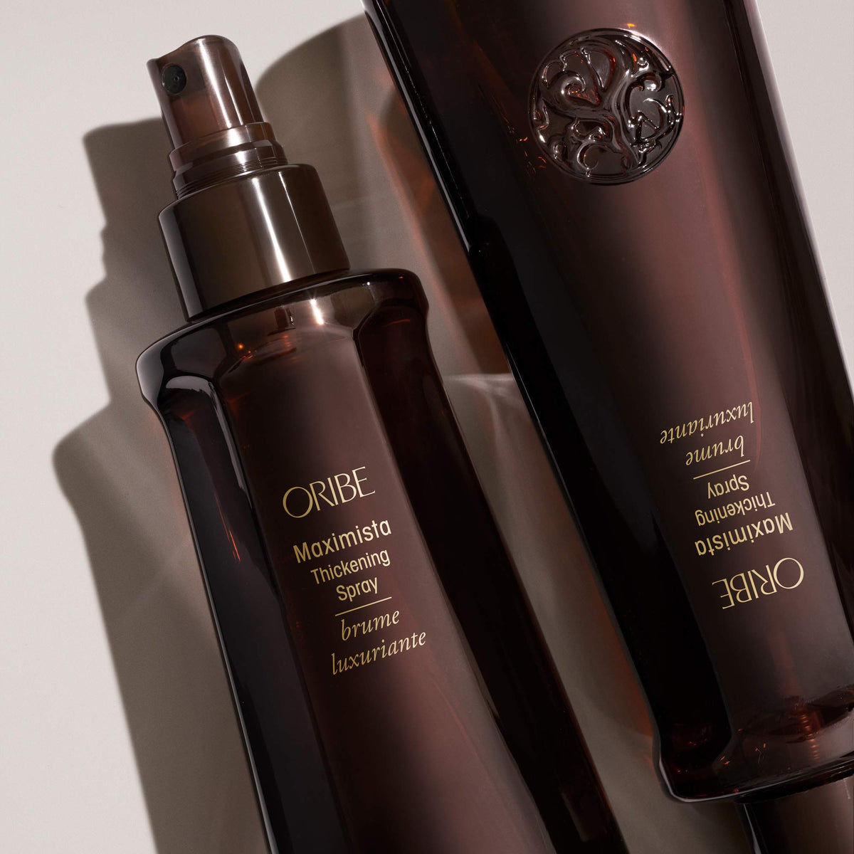 Oribe Maximista 6.8 oz bottle in hand to show scale and portable styling convenience