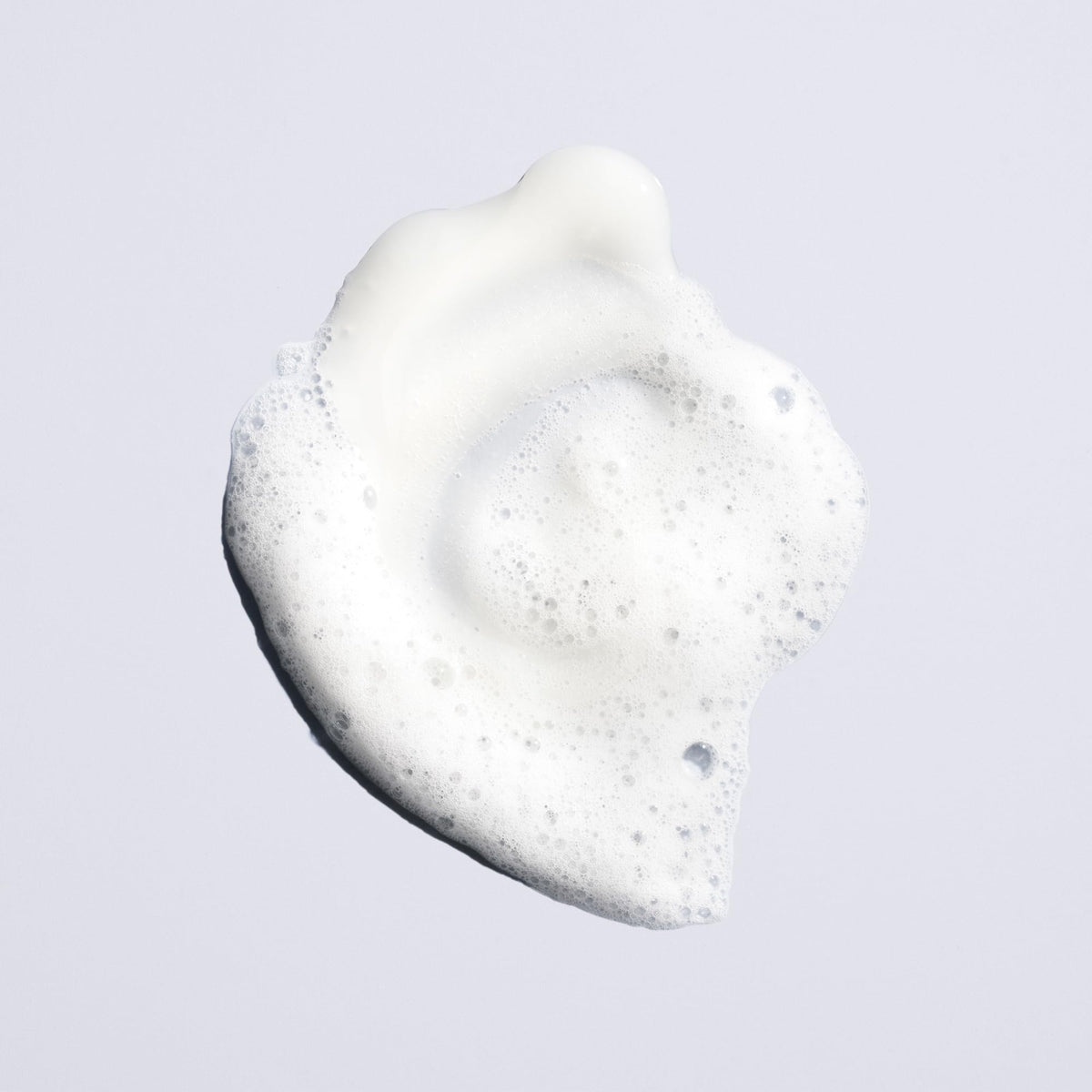 Oribe Run-Through bottle in hand to show 8.5oz scale and travel-friendly size