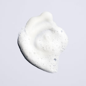 Oribe Run-Through bottle in hand to show 8.5oz scale and travel-friendly size
