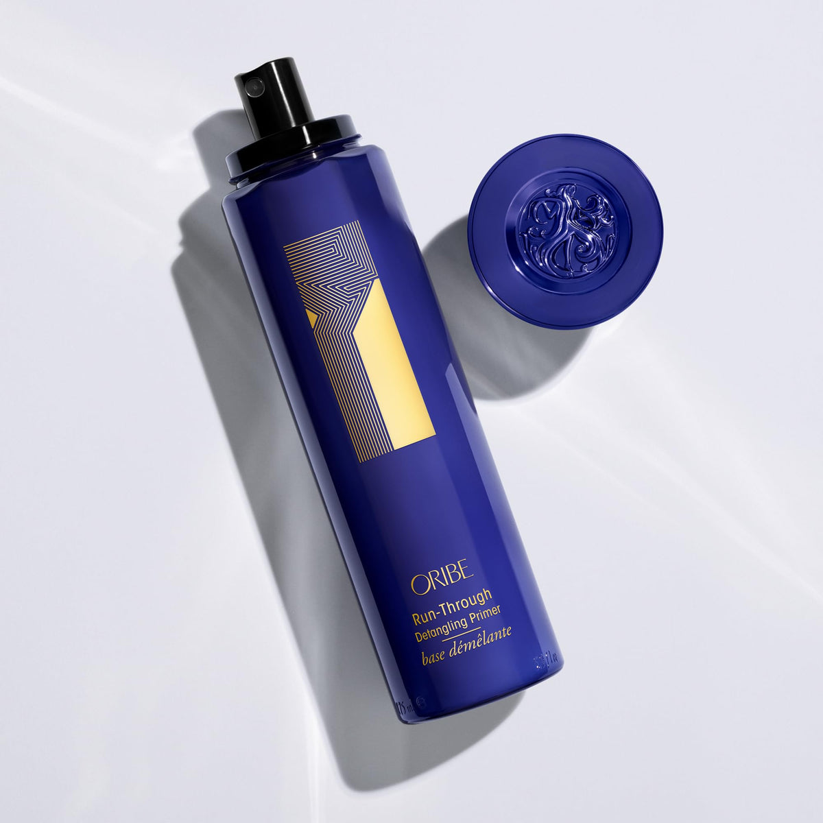 Oribe Run-Through held in hand to show 5.9oz scale and travel-friendly convenience