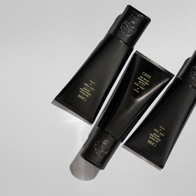 ORIBE bottle next to hand to show 5 oz size and travel-friendly benefit