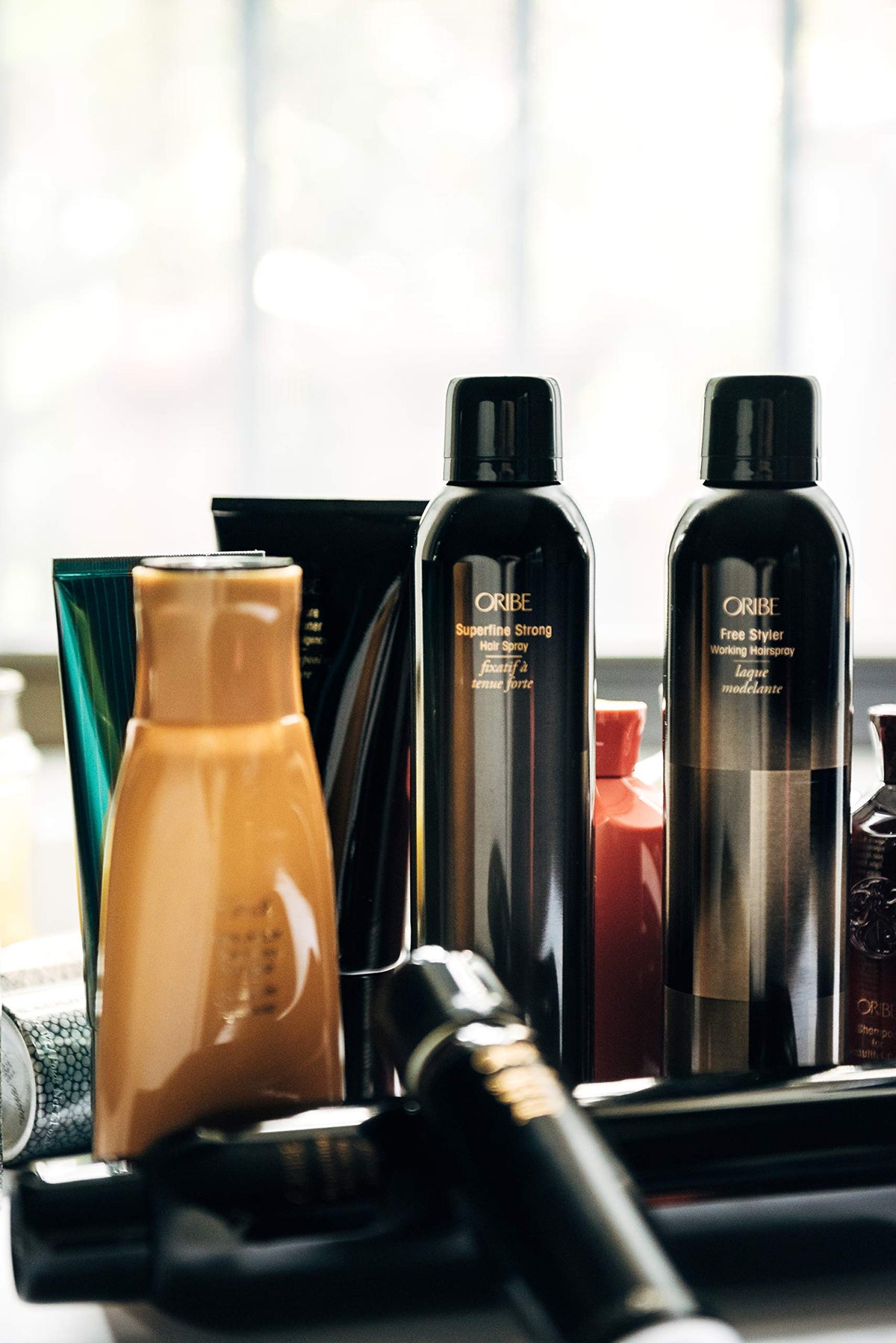Oribe hairspray in use during styling delivering salon hold and glossy finish