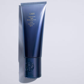 Oribe Supershine next to hand to show 5 oz scale and travel convenience