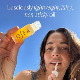 OSEA lip oil layered over lipstick demonstrating added shine and dimension benefit