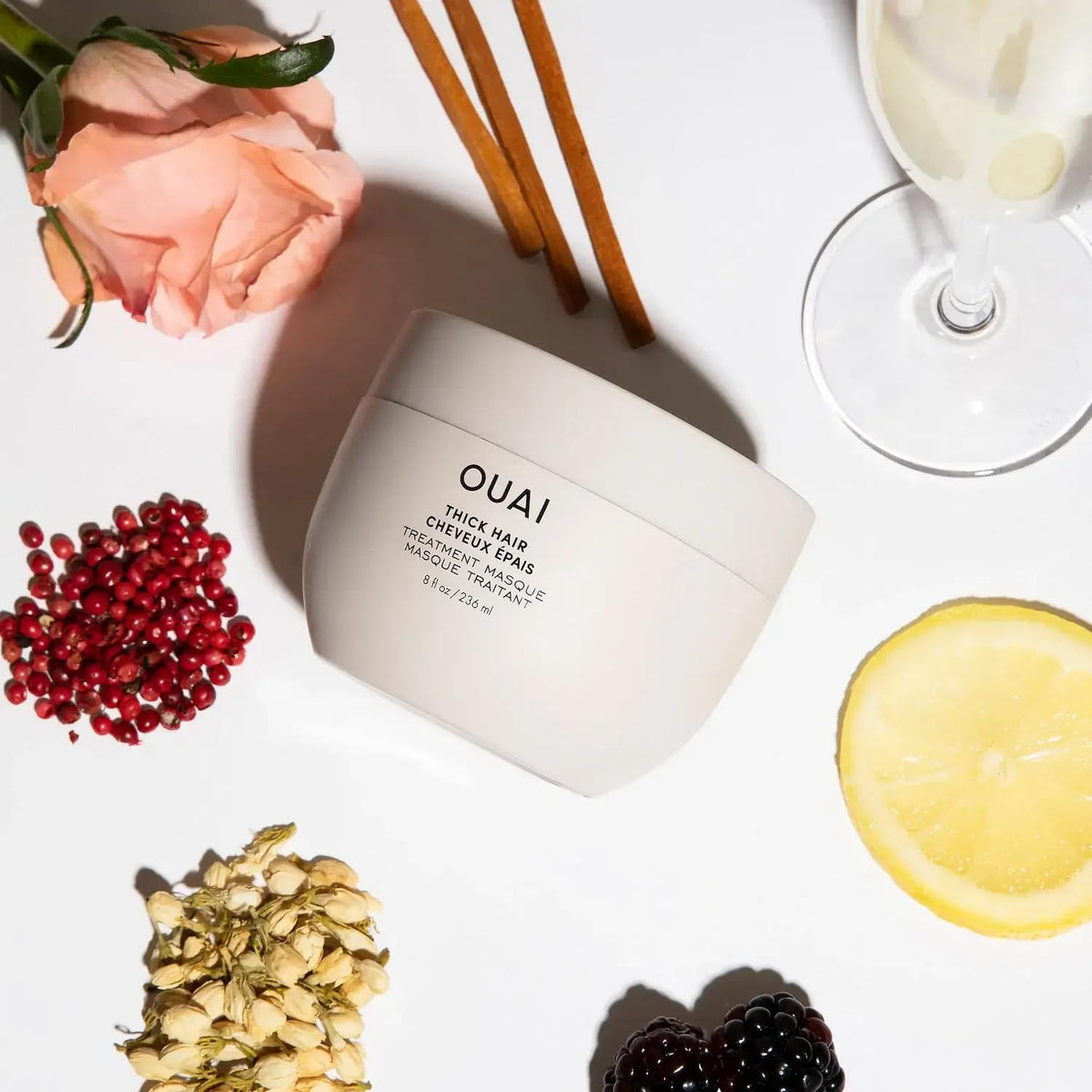 OUAI 3.4 oz masque next to common objects showing compact size for travel convenience