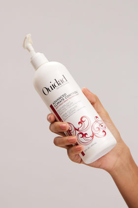 Ouidad 16 fl oz jar next to hand to show actual product size