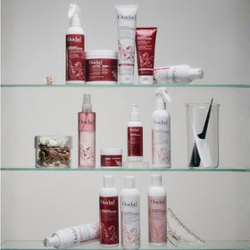 Travel-size Ouidad conditioner on a bathroom shelf showing portability and convenience
