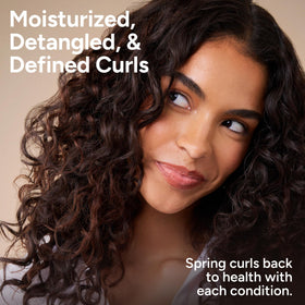 Ouidad conditioner being applied in shower to detangle and hydrate curls