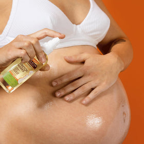 Palmer's oil being massaged into a pregnant belly to soothe and hydrate skin