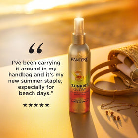 Pantene Sunkiss Glow bottle on beach towel evoking summer protection and portability