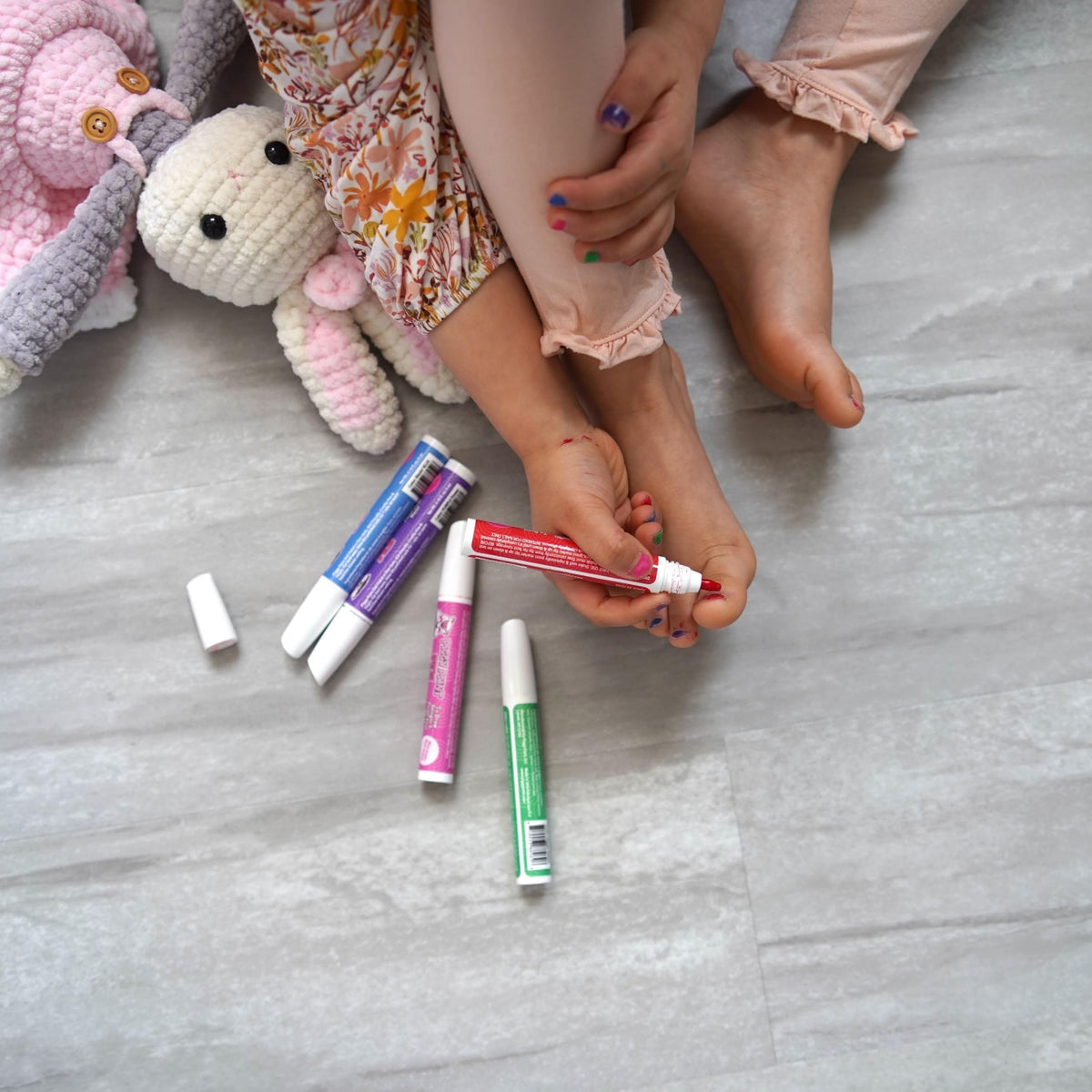 Child using Piggy Paint pen to color nails supervised by parent for safe application