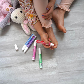 Child using Piggy Paint pen to color nails supervised by parent for safe application