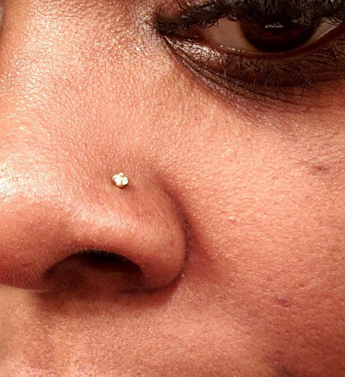 QWALIT piercing gun held between fingers to show scale and easy handling benefit