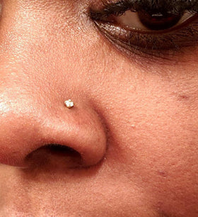 QWALIT piercing gun held between fingers to show scale and easy handling benefit