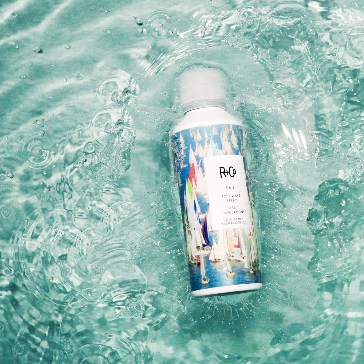 R+Co Sail being sprayed into hair for soft, touchable waves