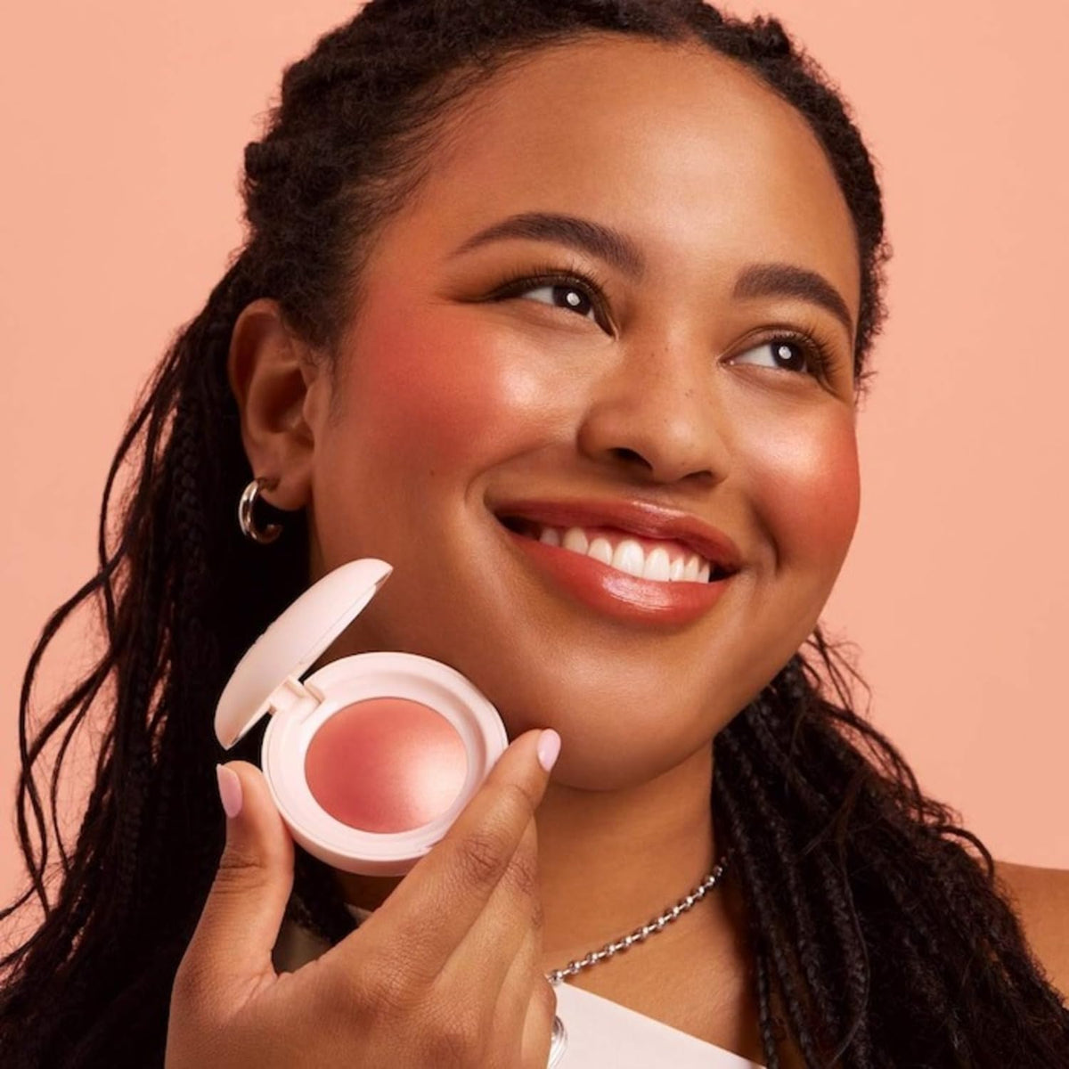 Rare Beauty model applying Joy on cheeks for natural radiance