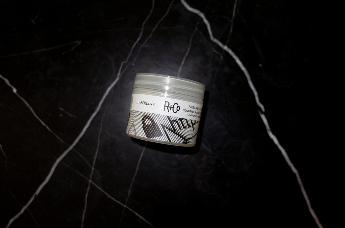 R+Co Hyperlink pomade in hand demonstrating easy spreadability and control