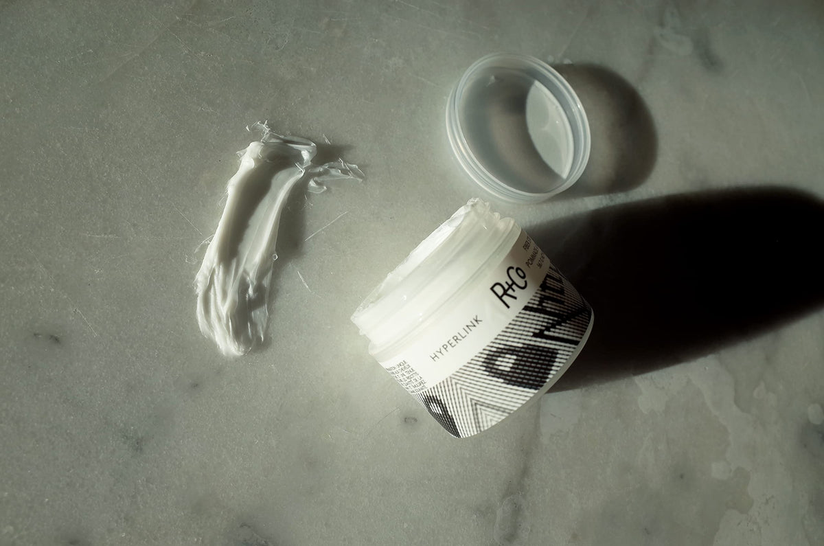 R+Co Hyperlink size and scale beside a hand showing convenient 2 oz travel size