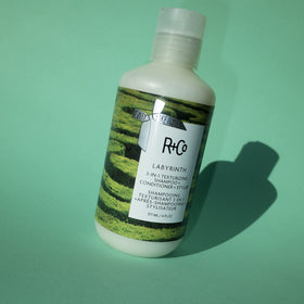 R+Co Labyrinth bottle next to hand to show true 6 oz scale and travel-ready size