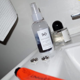 R+Co Spiritualized hands applying mist to hair for even distribution and gentle cleanse