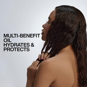 Redken travel-size oil in a toiletry bag showing portability and on-the-go care