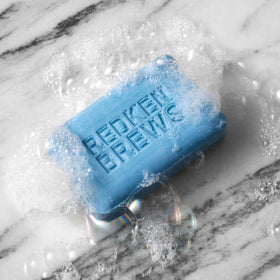 Redken Brews bar next to toiletries showing compact travel-ready benefit