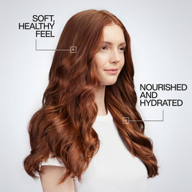 Stylist applying Redken One United to client prepping hair for heat styling