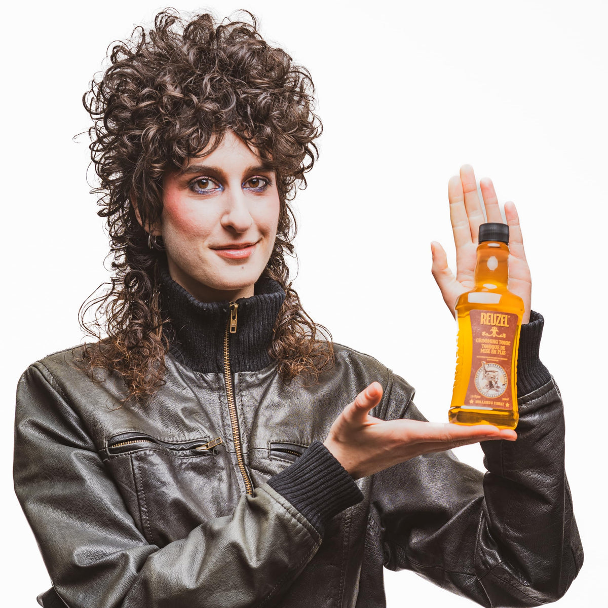 REUZEL bottle next to brush and dryer showing compatibility with heat styling tools
