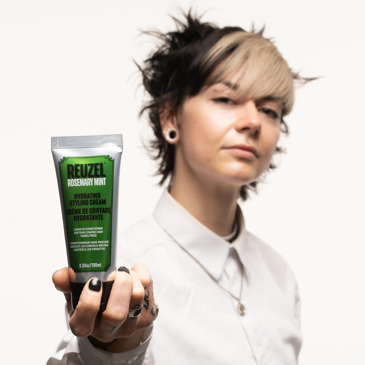 REUZEL cream held in hand to show 3.38 oz scale and travel-friendly convenience