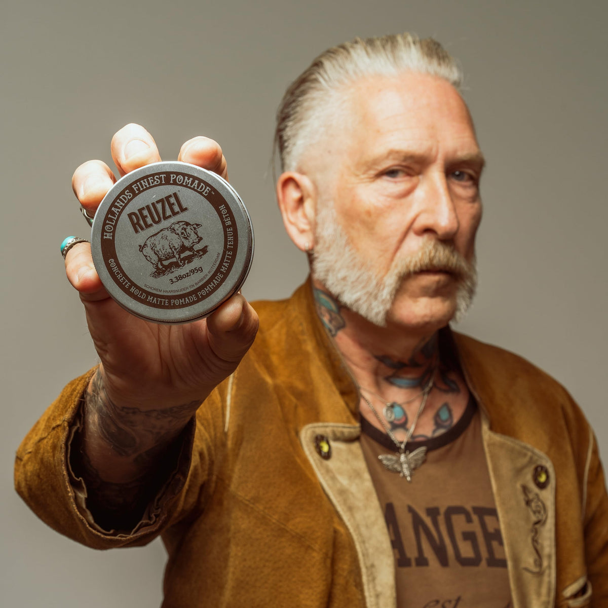 REUZEL pomade in travel pouch lifestyle scene showing portability and on-the-go grooming benefit