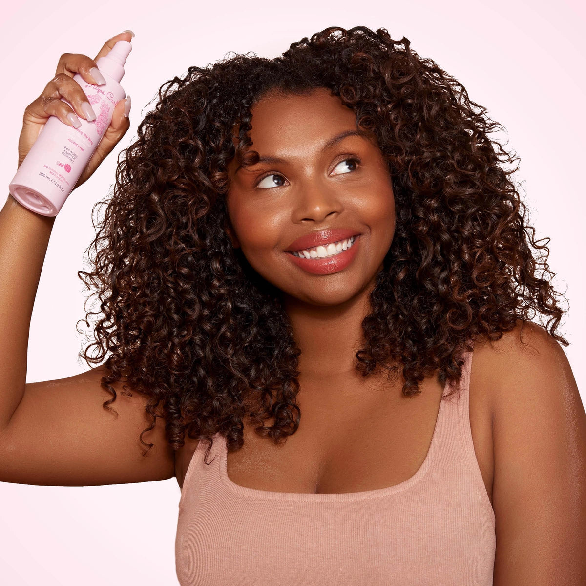 Rizos Curls spraying onto curly hair for defined bounce