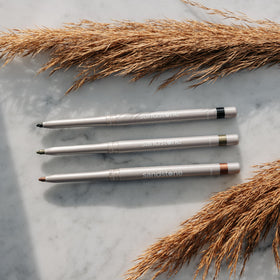 Sandstone Scandinavia pencil on vanity next to makeup items showing lifestyle use and travel-friendly size benefit