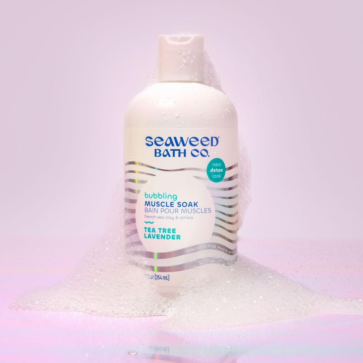 Seaweed Bath Co. 12 oz bottle beside hand showing portable size benefit