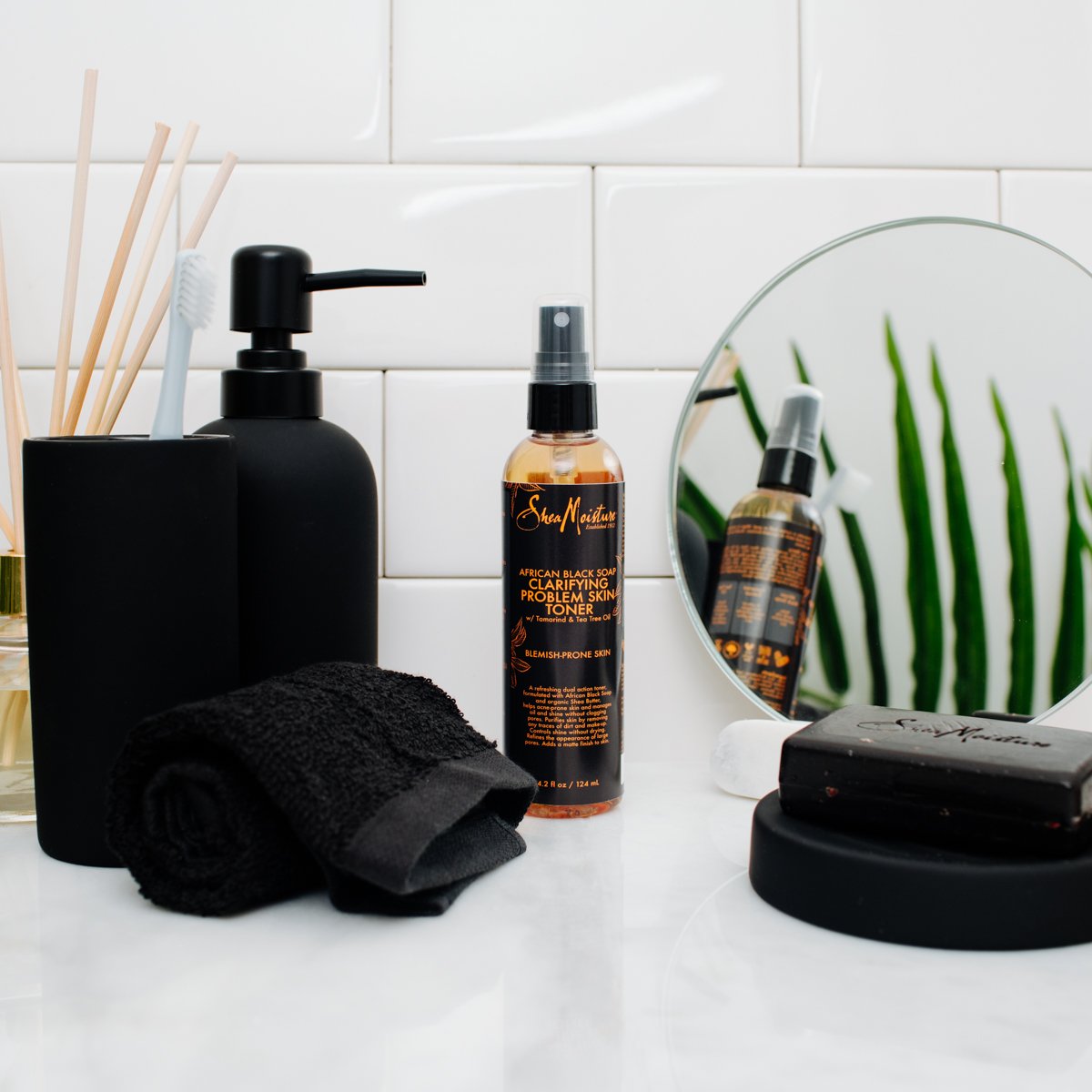 Shea Moisture tea tree oil and oats next to bottle emphasizing botanical blend