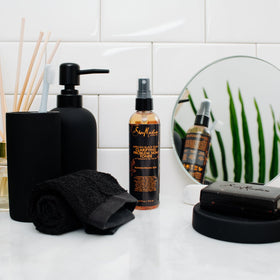 Shea Moisture tea tree oil and oats next to bottle emphasizing botanical blend