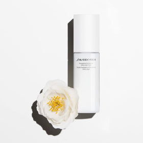 Shiseido 100 mL bottle beside common objects showing travel-friendly size