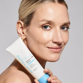 SKINN bottle next to hand showing 4 oz size and travel-friendly benefit