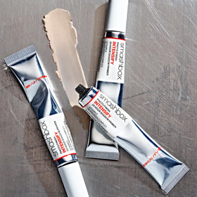 Size comparison of Smashbox 0.34 fl oz primer next to makeup brushes to show travel-friendly portability