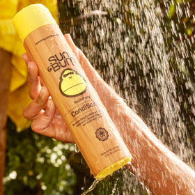 Sun Bum bottles held in hand showing 10 ounce scale and travel convenience