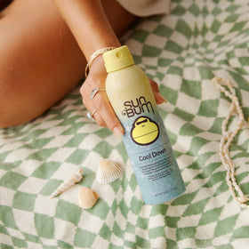 Sun Bum spray in hand applying mist to arm for easy coverage