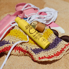 Sun Bum bottle in hand to show 3.4 oz travel scale and portability