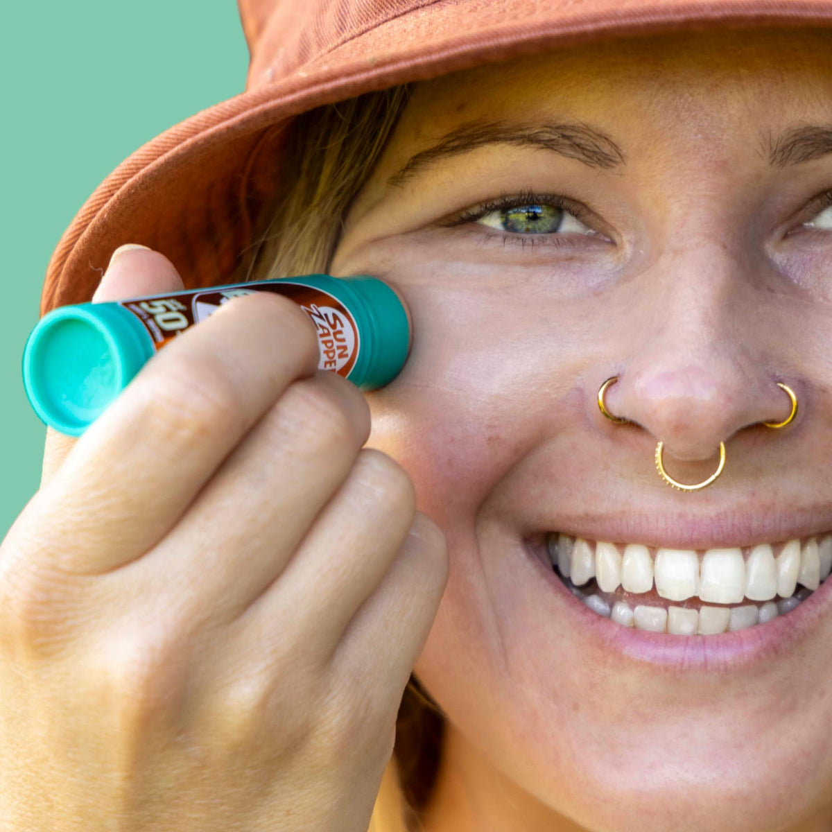 Sun Zapper applying stick to nose for visible sun protection