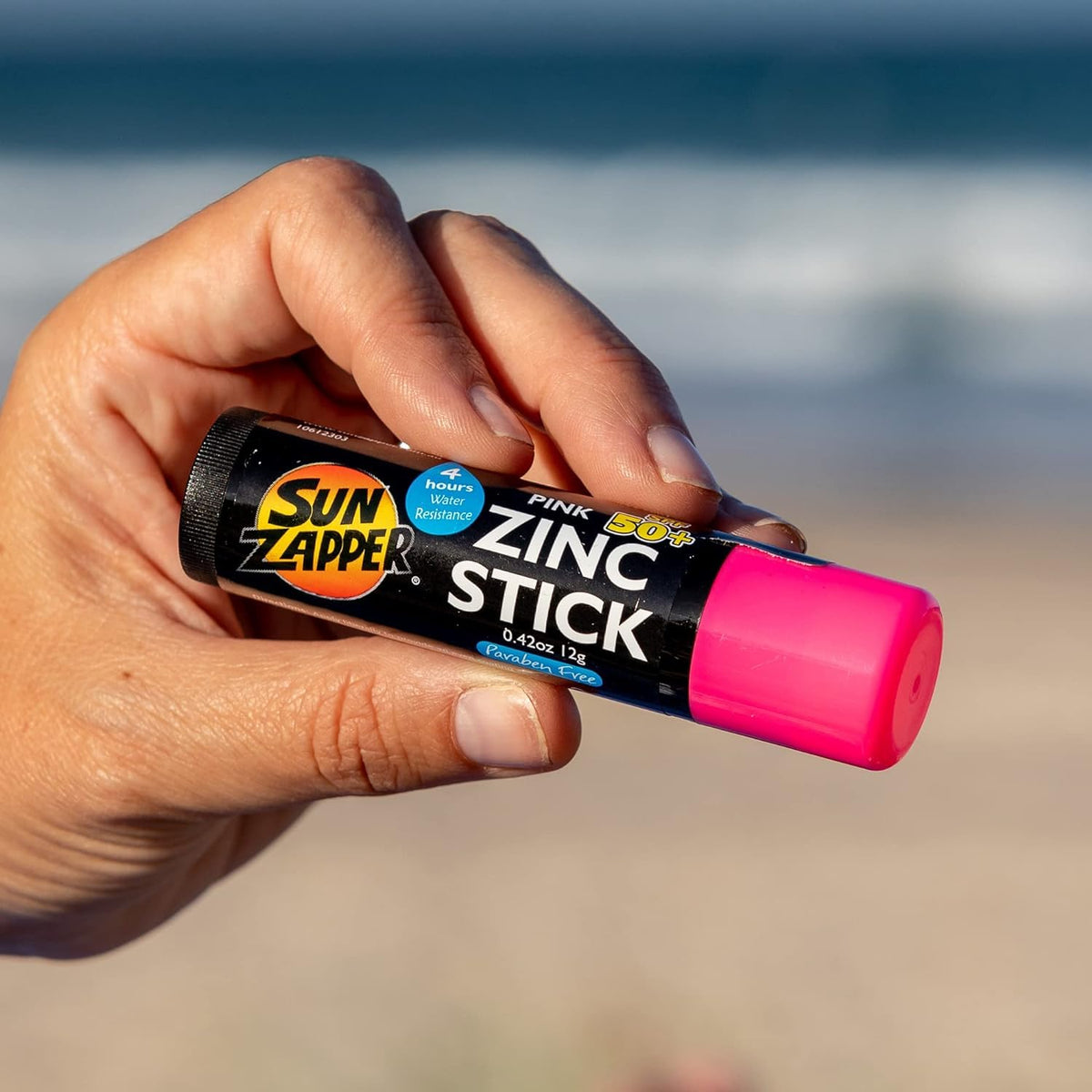 Sun Zapper stick held in hand to show travel-ready 12g size and portability