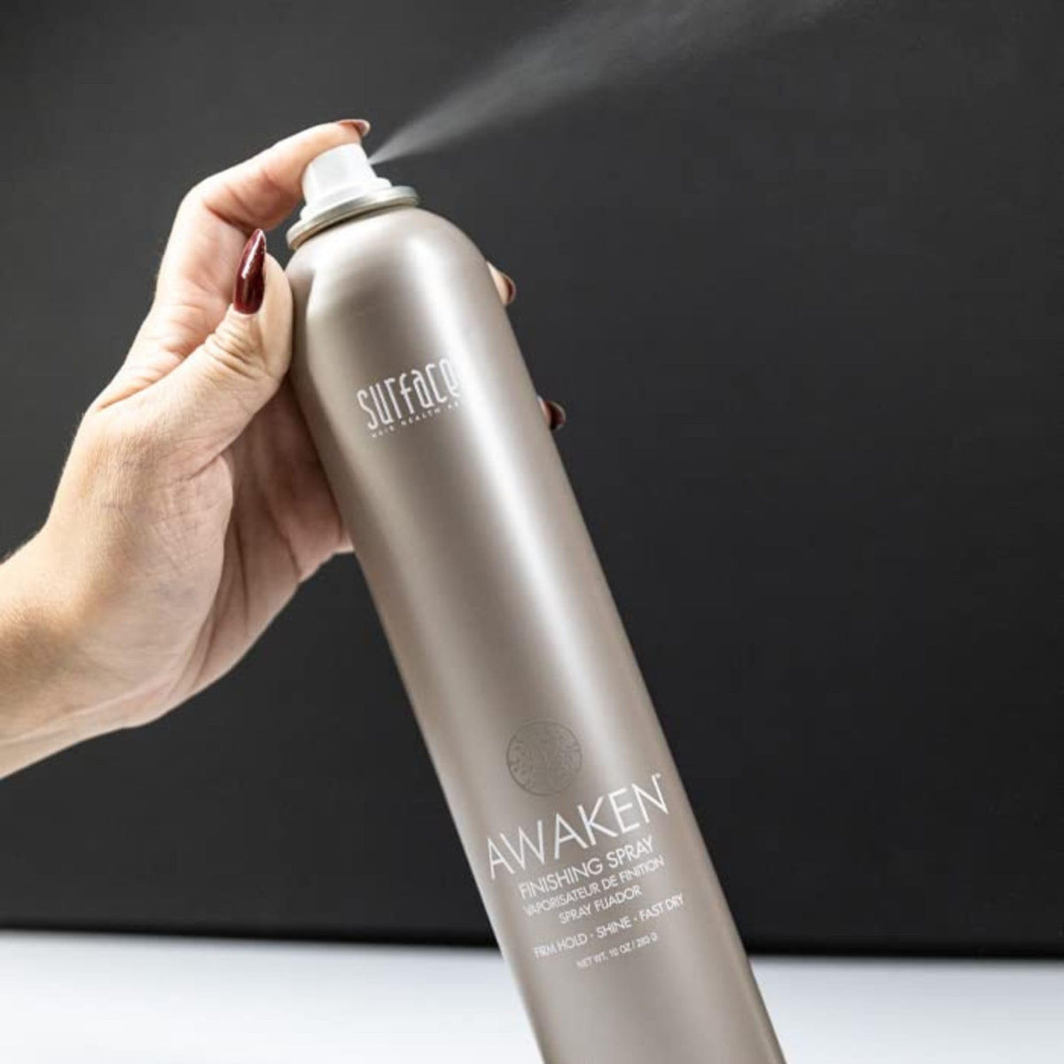SURFACE bottle held in hand for scale, illustrating travel-friendly 10 oz size