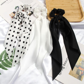 SUSULU scrunchie tied around a low bun adding a neat bow accent