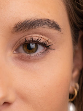 SWEED brow serum drop on fingertip highlighting lightweight texture for quick absorption